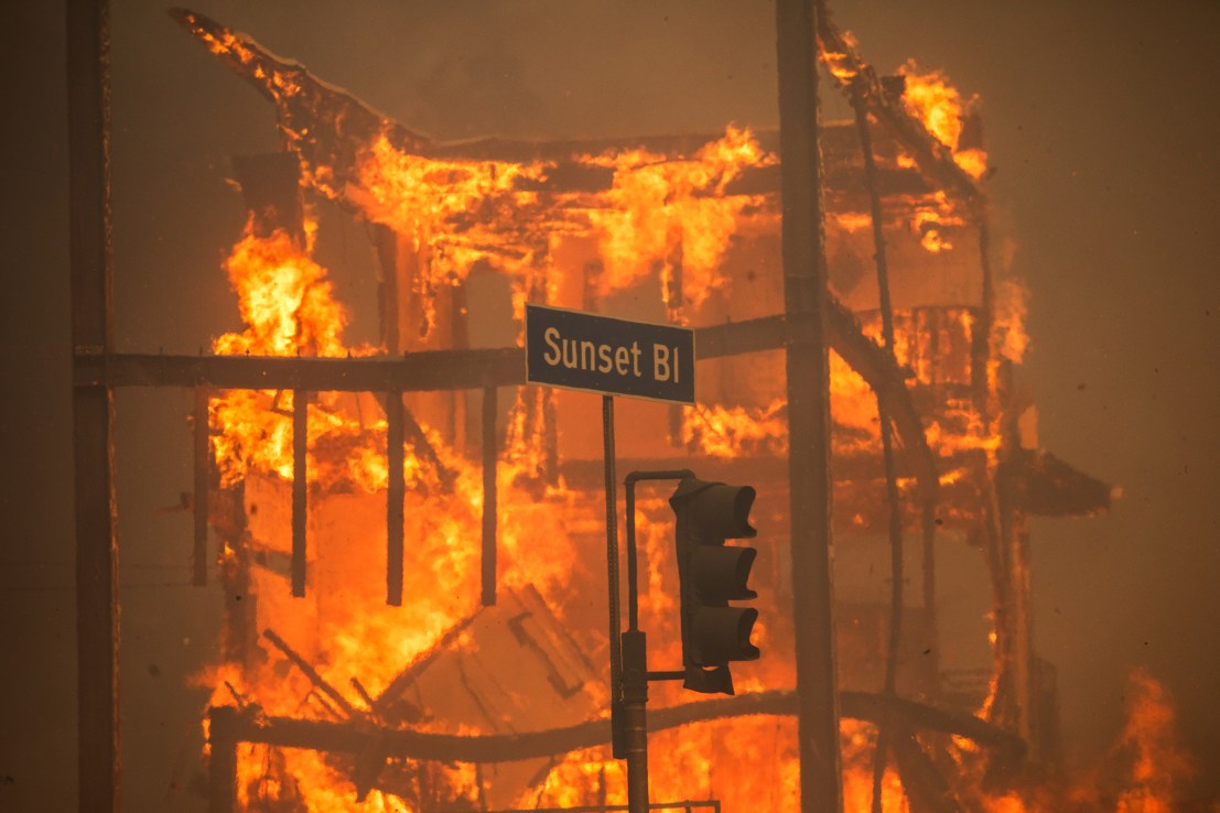 LOS ANGELES, CALIFORNIA - JANUARY 8: Flames from the Palisades Fire burn a building on Sunset Boulevard amid a powerful windstorm on January 8, 2025 in the Pacific Palisades neighborhood of Los Angeles, California. Fueled by intense Santa Ana Winds, the Palisades Fire has grown to over 15,000 acres and 30,000 people have been ordered to evacuate while a second major fire continues to burn near Eaton Canyon in Altadena.  (Photo by Apu Gomes/Getty Images)
