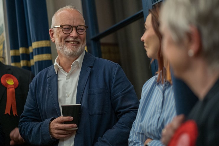Jason Stockwood, a notable business leader, engaged in a strategic discussion at a corporate event, wearing a tailored suit.