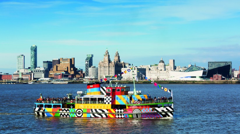 Mersey Ferry Snowdrop adorned in vibrant Dazzle design sailing on the River Mersey against a clear blue sky