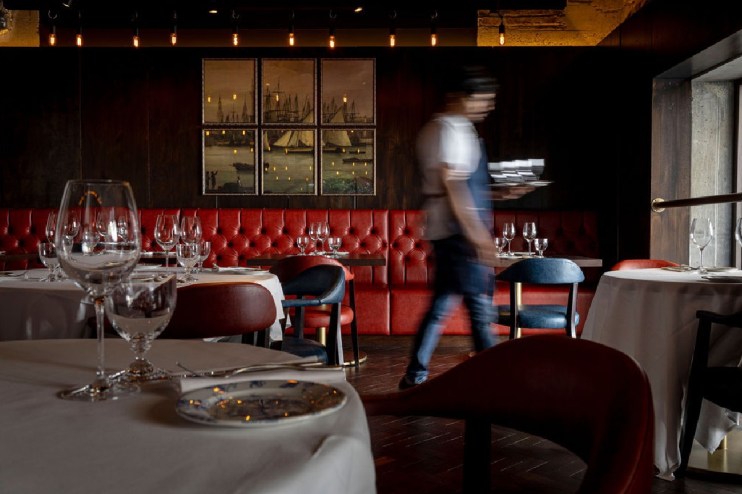 Chop house interior with rustic decor, featuring wooden tables, ambient lighting, and patrons enjoying meals.
