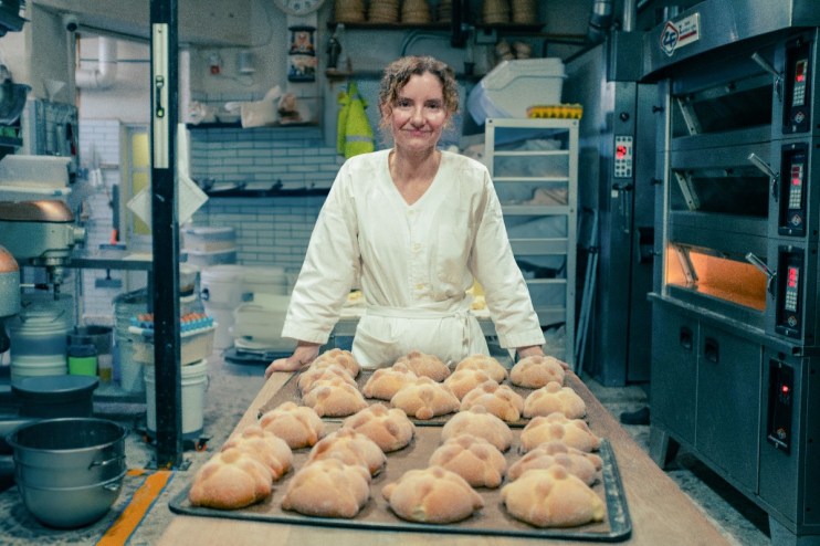 Elena giving a speech at a business conference podium, audience engaged, emphasizing leadership and innovation strategies