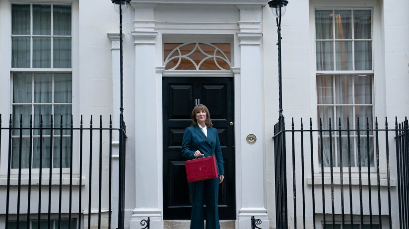 Breaking news scene with reporter holding microphone, surrounded by cameras in front of a bustling city backdrop