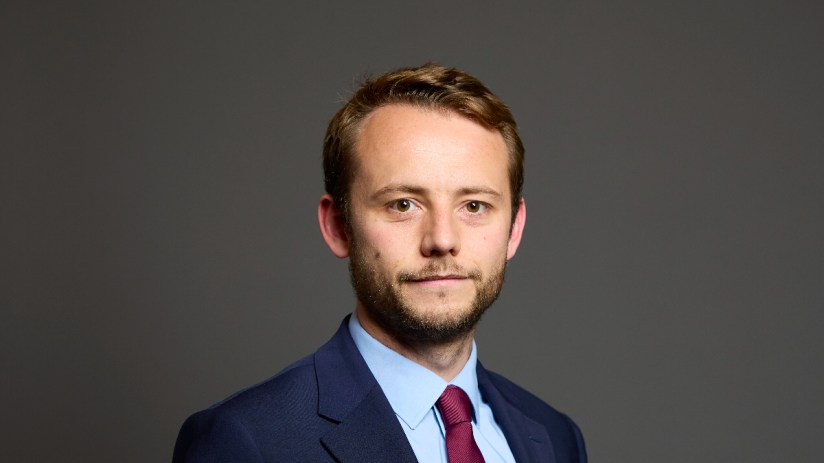Chris Curtis at House of Commons event, wearing formal attire, engaged in a discussion on current political matters.