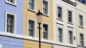 Luxurious mansions surrounded by manicured gardens in an upscale residential neighborhood, highlighting opulent housing tr...