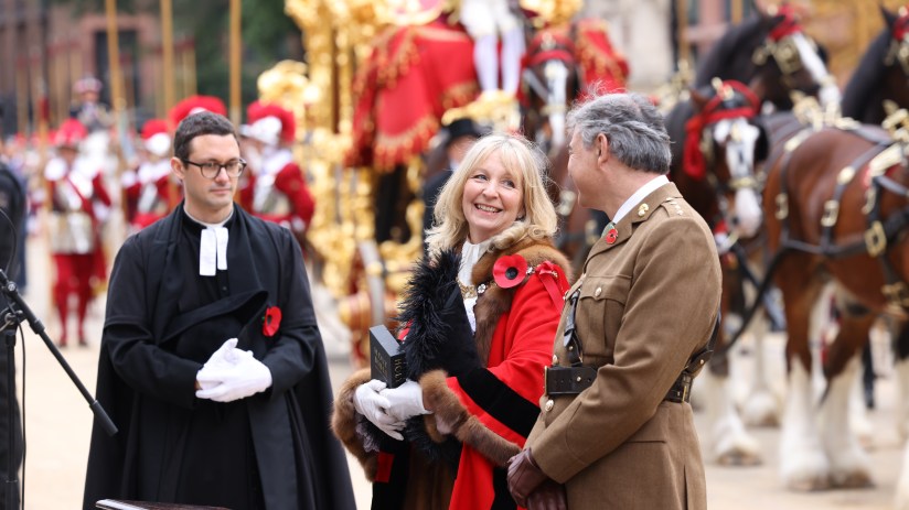 Breaking news event with large crowd gathered at a press conference, diverse attendees listening attentively to keynote sp...