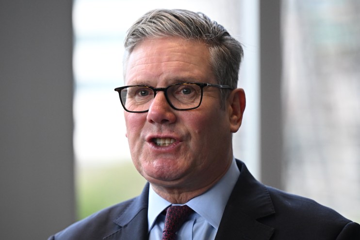 Keir Starmer speaking at a podium during a press conference, wearing a suit and tie, addressing political issues.