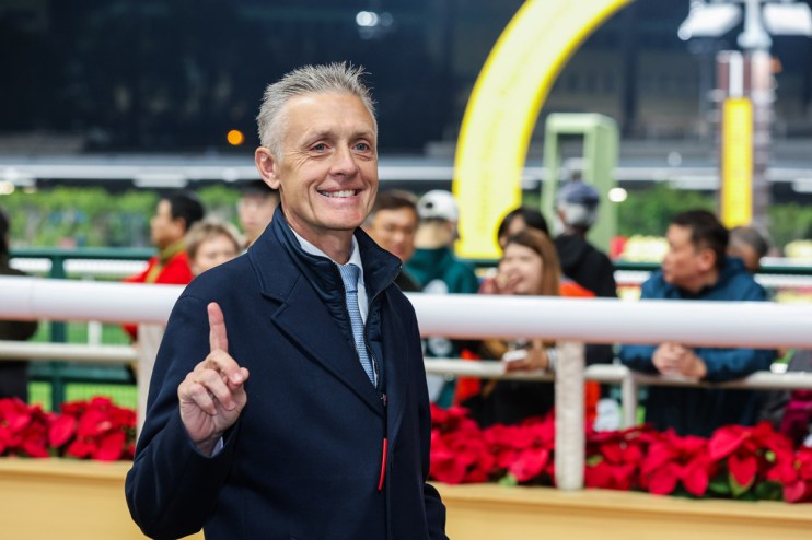 Mark Newnham presenting at a business conference, wearing a suit and tie, addressing an audience in a well-lit room.
