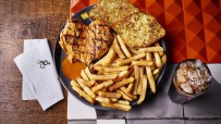 Nandos Chicken Butterfly with PERi-salted chips, garlic bread, and a bottomless Coke Zero on a restaurant table