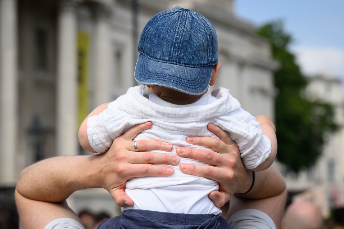 LONDON, ENGLAND - JUNE 11: A man holds his son as he gives him a shoulder ride, during a protest calling for longer paternity leave for fathers, on June 11, 2025 in London, England. Fathers and non-birthing parents are picketing in protest of the UK's paternity leave policy, ahead of Father's Day on June 15. Campaigners from 'The Dad Shift,' organizers of the strike, have said the UK's statutory two week paternity leave, which is paid at less than 50% of the National Living Wage, is one of the worst in Europe and the developed world. (Photo by Leon Neal/Getty Images)