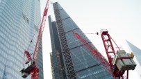 Construction crane towering over modern office buildings under clear blue sky, symbolizing urban development and business ...