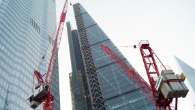 Construction crane towering over modern office buildings under clear blue sky, symbolizing urban development and business ...
