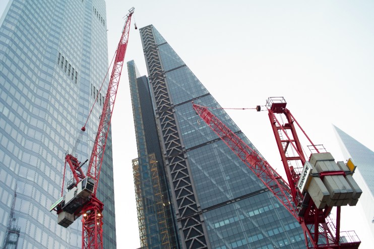 Construction crane towering over modern office buildings under clear blue sky, symbolizing urban development and business ...