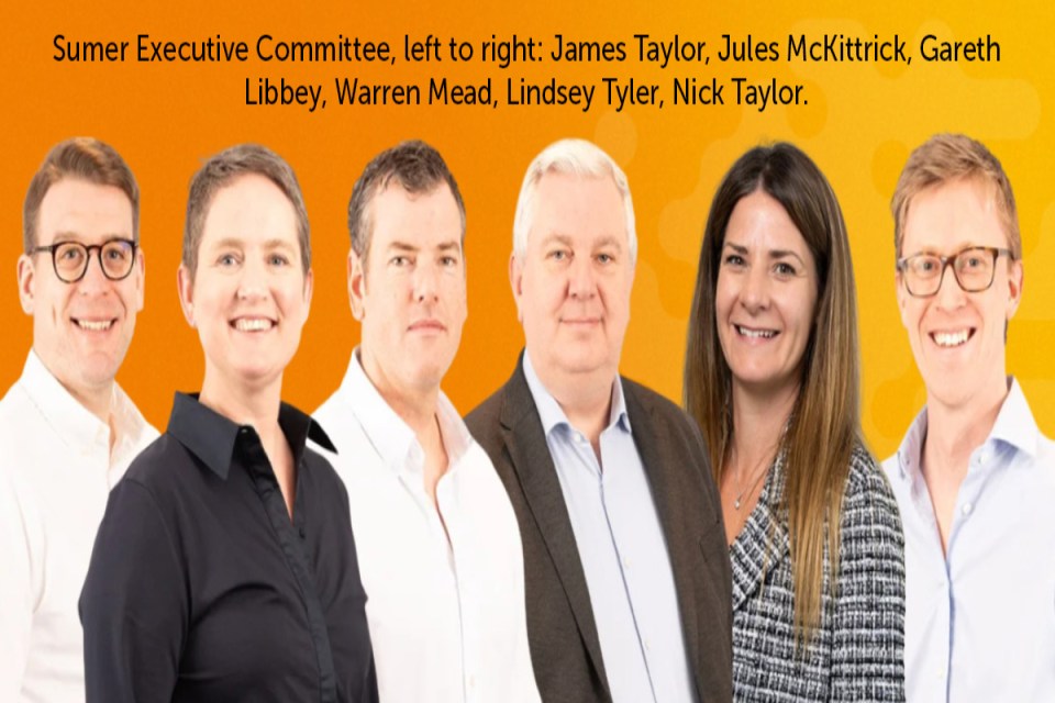 Sumer executive team gathered in a modern office setting discussing strategic plans, showcasing leadership and collaboration