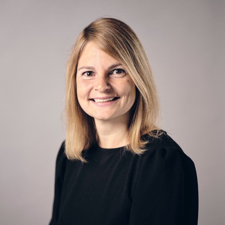 Janine Hirt smiling in professional attire, highlighting her role in business leadership and innovation