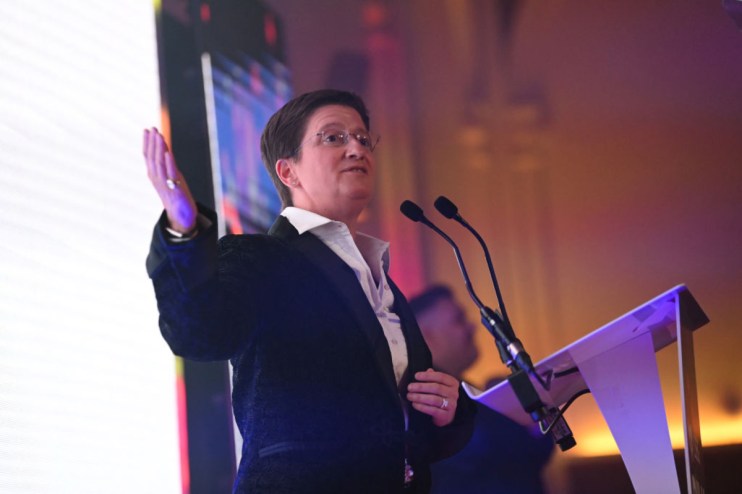 Julia Hoggett speaking at a business conference podium, emphasizing key financial strategies and market insights.