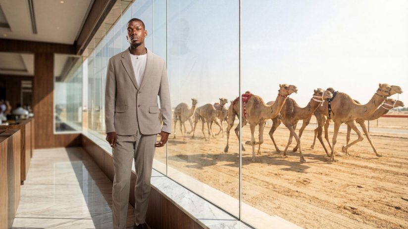Paul Pogba holding a contract while standing beside Al Haboob racing team logo, celebrating his new shareholder and ambass...
