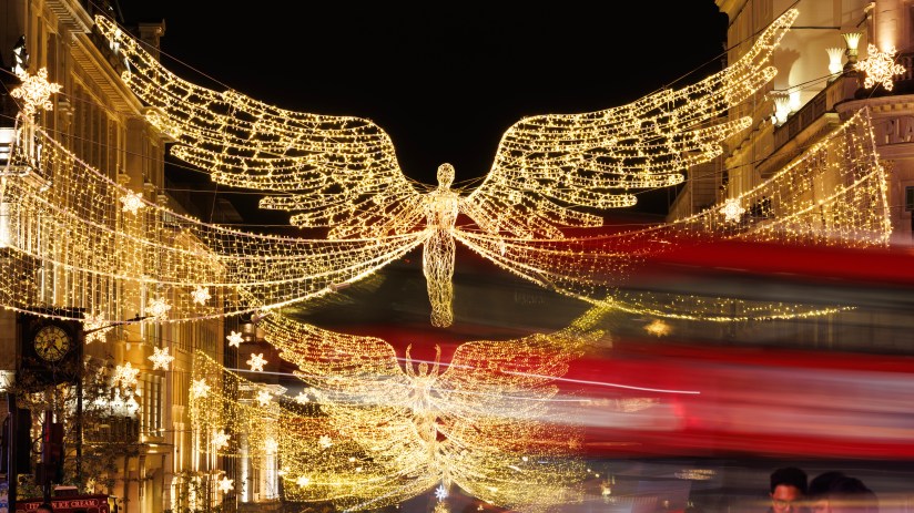 Regent Street bustling with pedestrians and iconic red double-decker buses under clear skies in a lively city scene