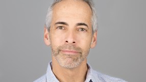 Russ Shaw in a business suit speaking at a tech conference podium, emphasizing innovation and digital transformation.