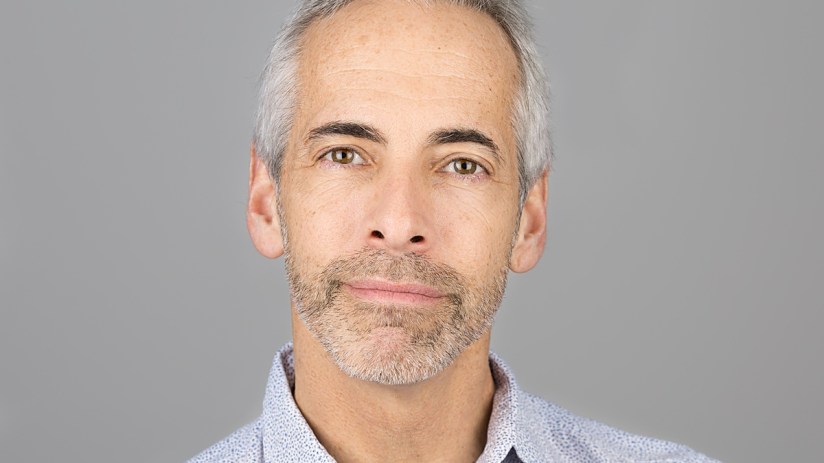 Russ Shaw in a business suit speaking at a tech conference podium, emphasizing innovation and digital transformation.