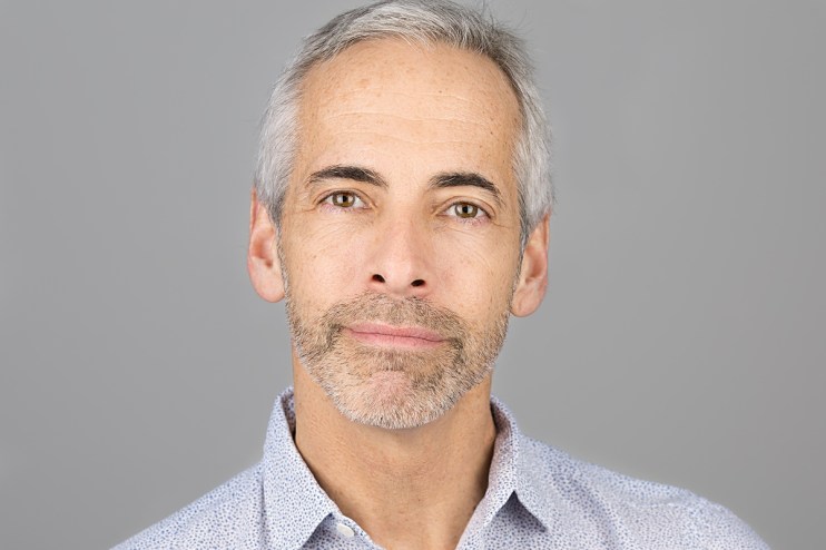 Russ Shaw in a business suit speaking at a tech conference podium, emphasizing innovation and digital transformation.