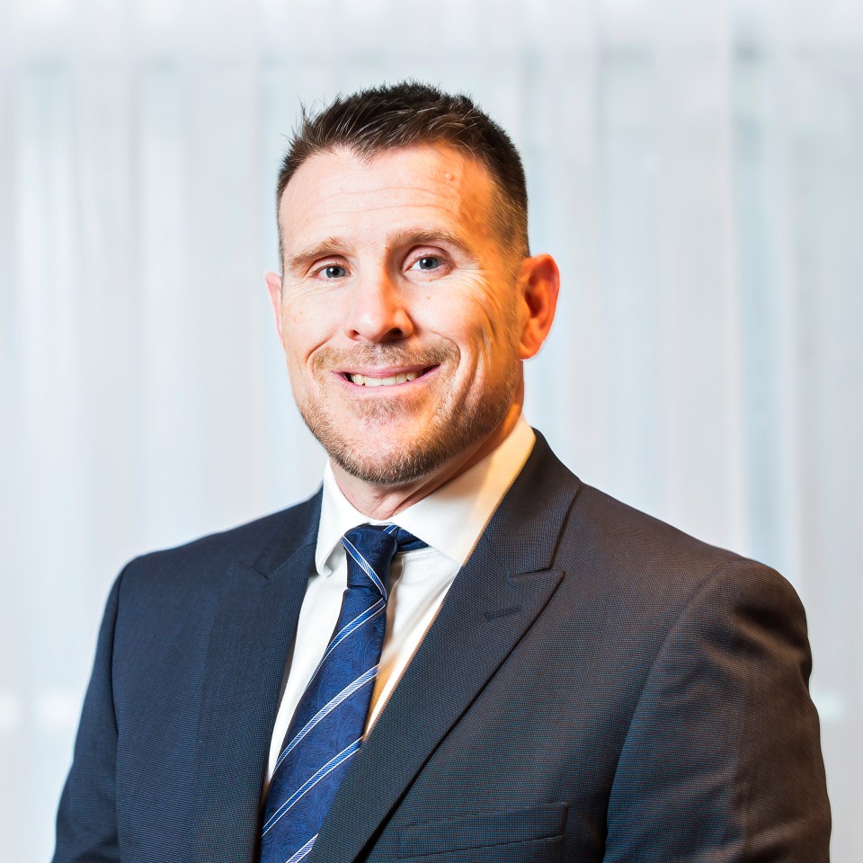 Thomas Pearson speaking at a press conference podium against a backdrop of cityscape and business leaders.