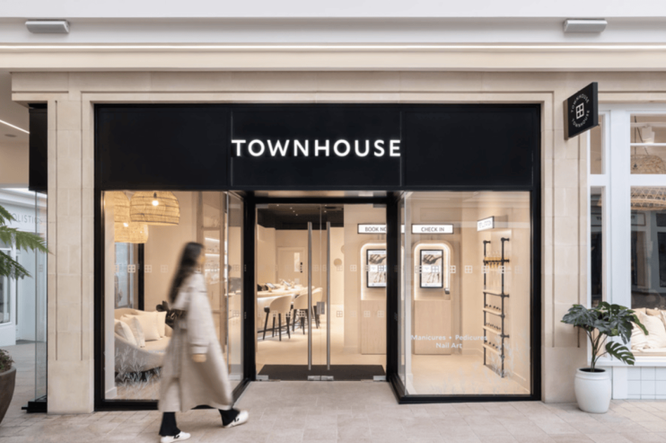 Modern townhouse exterior with brick facade, large windows, and neatly landscaped front yard on a sunny day