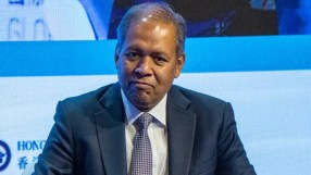 Venkat speaking at a conference podium with a presentation slide in the background, addressing a professional audience