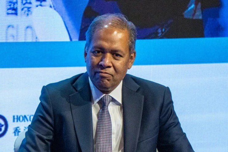 Venkat speaking at a conference podium with a presentation slide in the background, addressing a professional audience