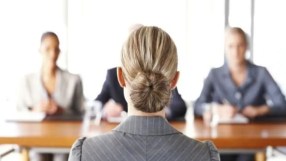 Professional job interview setting with diverse candidates seated at a table, highlighting workplace diversity and inclusion.