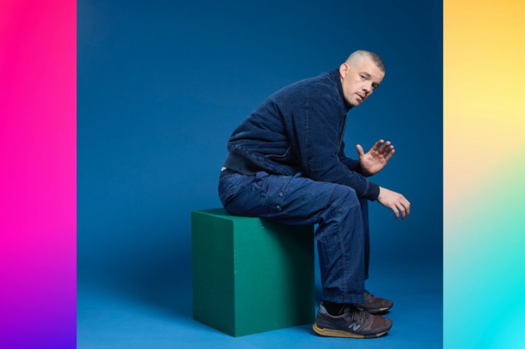 Russell standing against a dynamic swirly background, conveying energy and movement, suitable for a business news setting