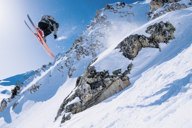 Expert skier carving through fresh powder on a sunny mountain slope, showcasing advanced skiing techniques and winter spor...