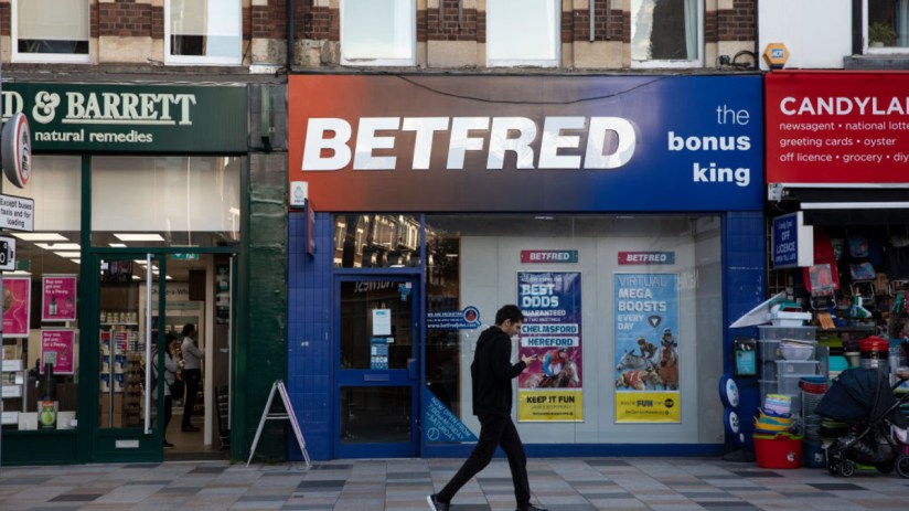 Betfred storefront with prominent signage, displaying current promotions and customers entering and exiting the shop