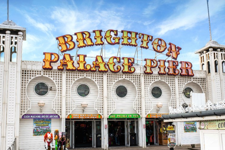 Brighton Palace Pier against a vibrant sunset, bustling with visitors enjoying the iconic seaside attraction and lively at...