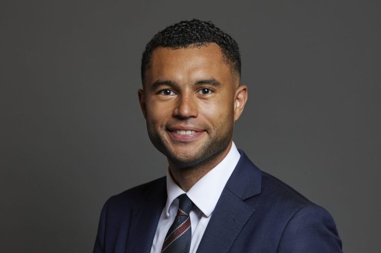 Callum Anderson MP in formal attire standing confidently in front of the parliament building
