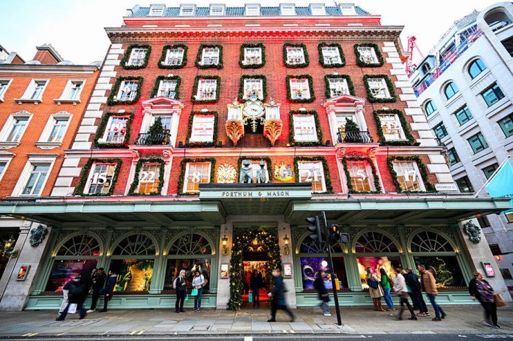 Fortnum store facade with elegant window displays and iconic clock on bustling London street