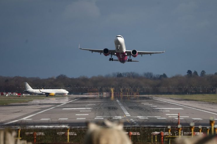 Gatwick Airport terminal bustling with travelers and staff under bright signage and flight information displays