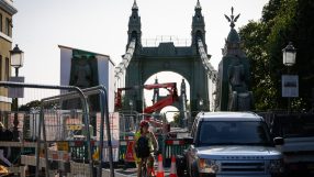 Hammersmith Bridge spanning the River Thames, surrounded by lush greenery and clear blue skies, capturing its iconic archi...