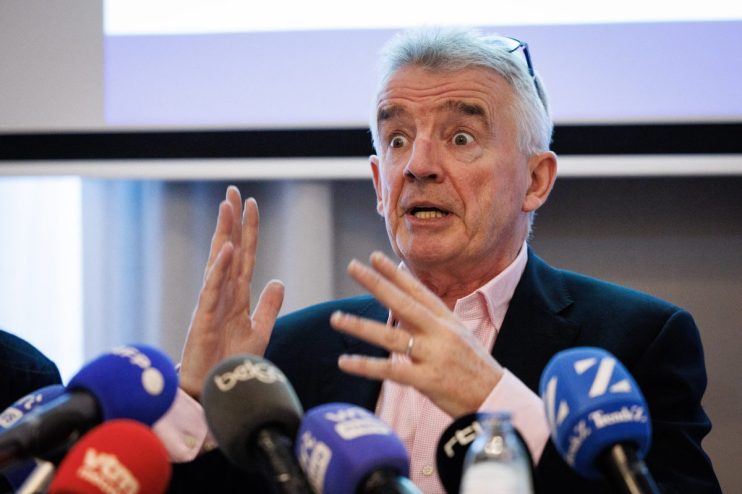 Michael OLeary speaking at a business conference, wearing a suit and gesturing with hands, emphasizing a point to the audi...