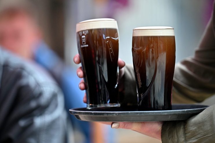 Pints of Guinness on a bar counter in UK pub, highlighting traditional British pub culture and popular beer choice