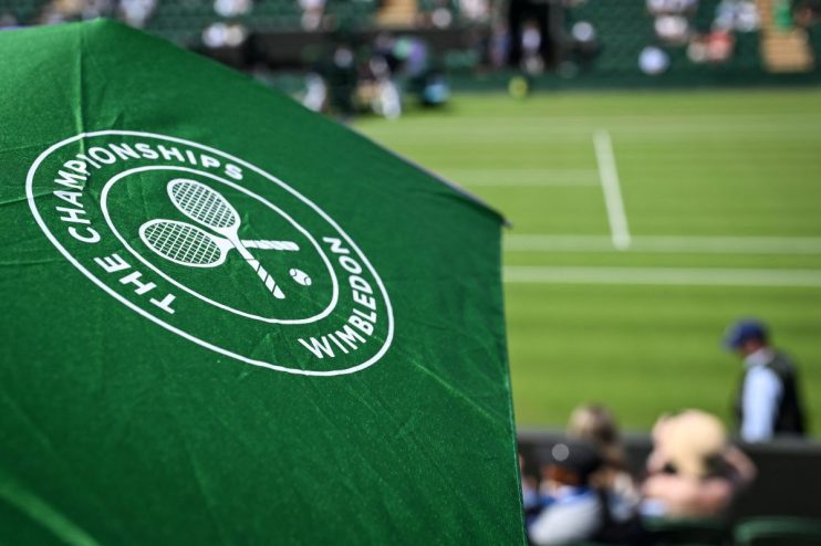 Wimbledon tennis match with players in action on grass court, surrounded by packed audience under clear skies