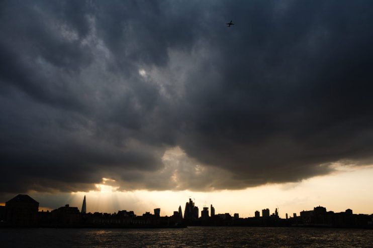 Severe weather impacts business operations with storm clouds looming over a city skyline, highlighting economic challenges.