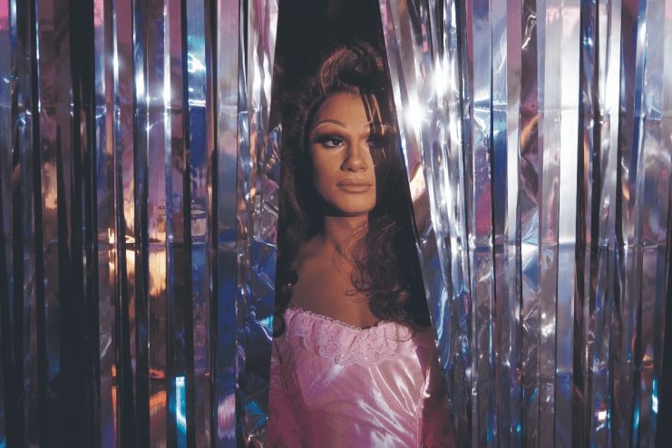 Breaking news event featuring a large crowd gathered in a city square, with banners and diverse participants engaging acti...