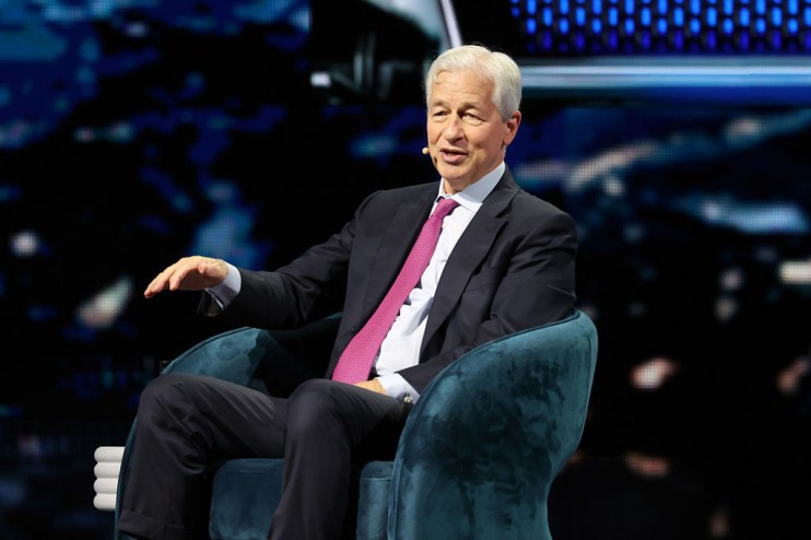 Jamie Dimon speaking at a JP Morgan event, wearing a suit and tie, addressing financial trends and market strategies.