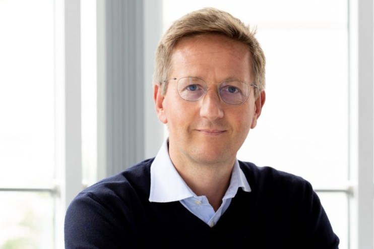 Oliver Holbourn in a professional setting discussing financial strategies and market trends in a business conference room.