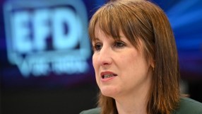 Keanu Reeves at a press conference with journalists, wearing a tailored suit and engaging with the media in a professional...