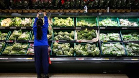 Tesco supermarket exterior showcasing brand signage and entrance with shoppers entering and exiting the store.