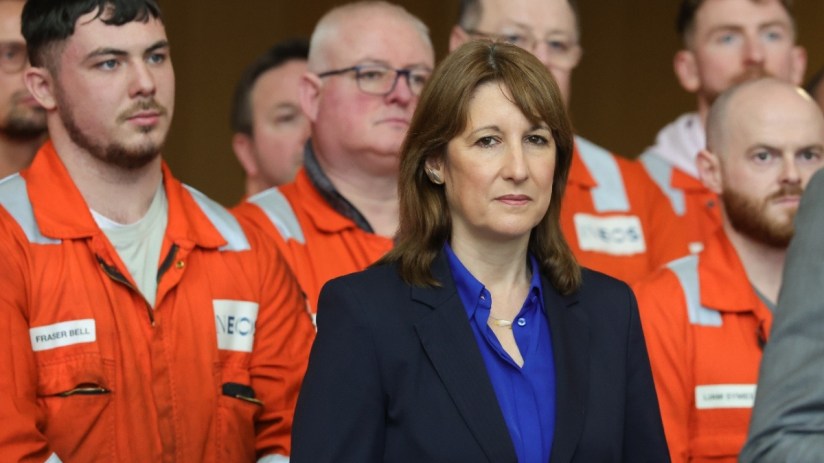 Breaking news scene with reporters at a press conference, microphones on a podium, and a large crowd in the background