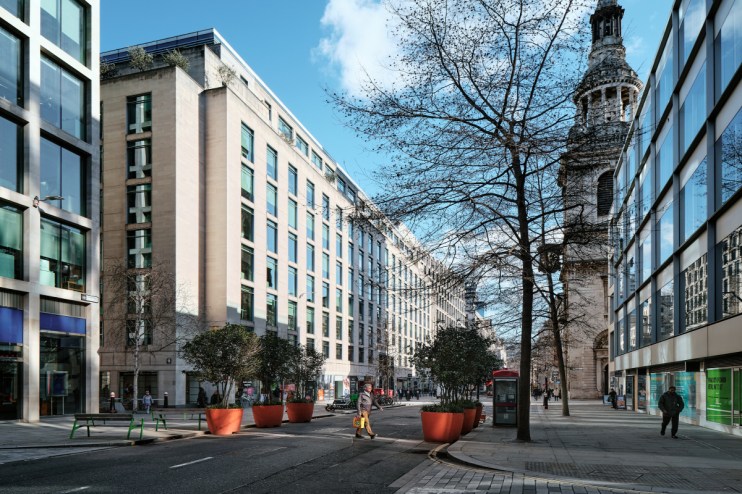 Four businessmen crossing Cheapside road in London during daytime, highlighting urban commuting and professional attire.