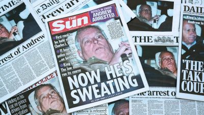 Andrew Mountbatten Windsor reading newspapers, possibly discussing current events or related news topics, in a formal setting