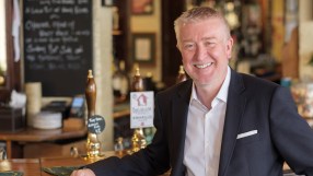 Chris Jowsey presenting at a business conference, wearing a suit and tie, engaging with an audience in a modern conference...